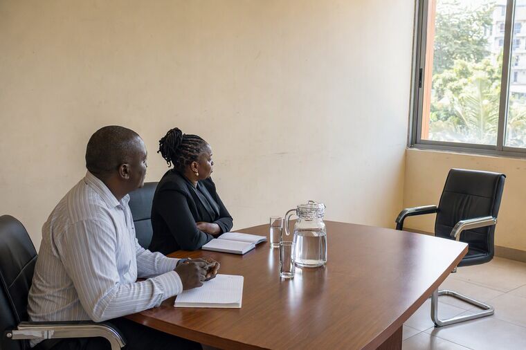 Two interviewers at a table with the chair opposite them empty