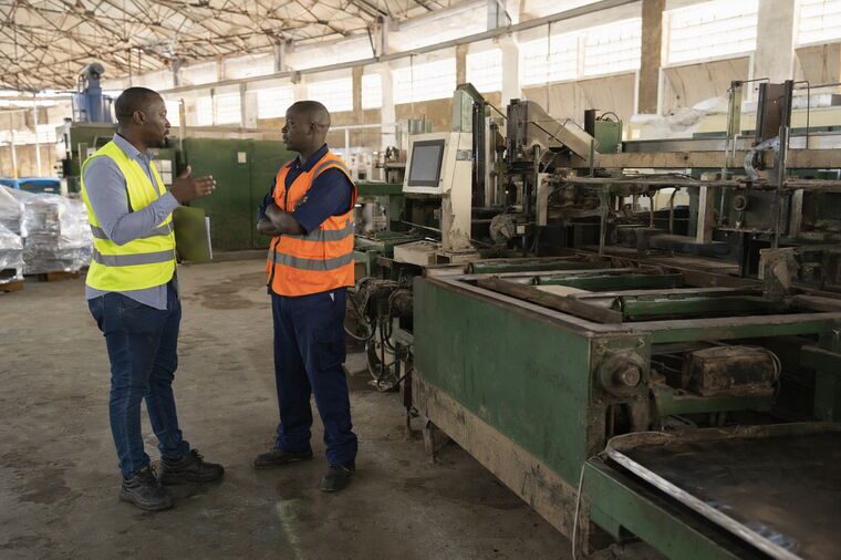 A supervisor and an operator talking beside a stilled machine